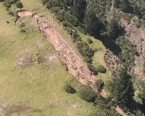 Aerial photo of steep hill country land showing a landslip between two power poles.