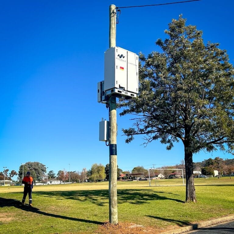 A wooden power pole with a battery energy storage system or BESS installed on it.