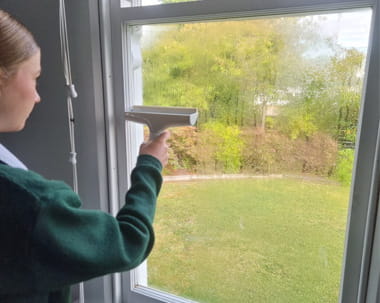 Girl using a scoopy on window to remove condensation