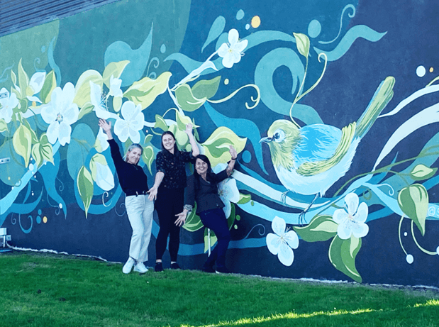 Three people standing infront of a painted bird mural in Te Puke